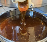 honey being poured into a pot on a stove