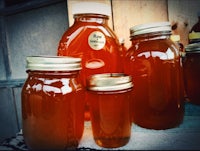 three jars of honey sitting on a wooden table