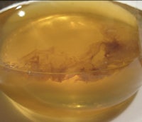 a yellow liquid in a bowl on a white plate